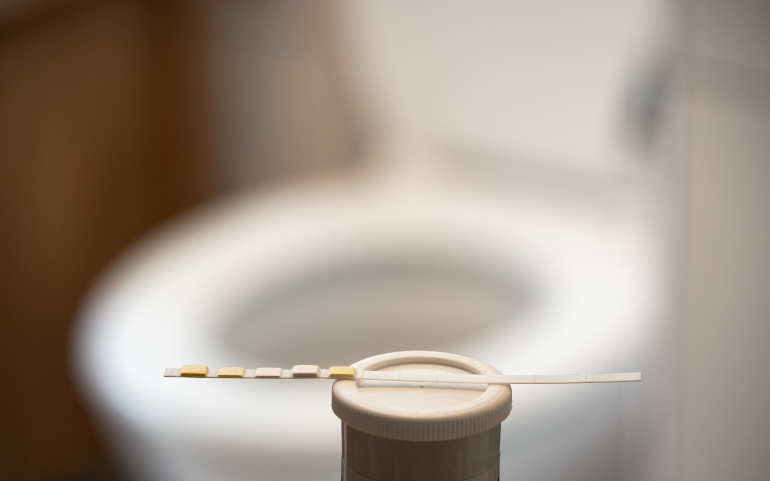 Unbenutzter Teststreifen vor einer Toilette zu Hause, Konzept einer Blasenentzündung